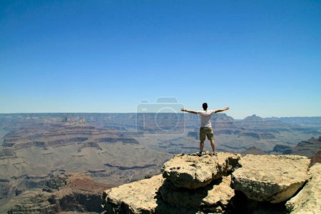 Photo for Young man in front of the Grand Canyon scenery - feeling of freedom, success - Royalty Free Image