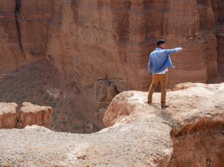 Hombre con camisa de mezclilla tomando una foto de teléfono inteligente de Charyn Canyon en Kazajstán