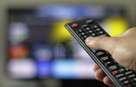 Foto de Un atracón viendo un programa de televisión - la mano sosteniendo un control remoto - Imagen libre de derechos