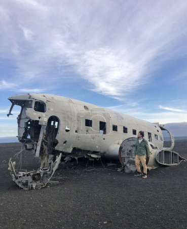 Man standing next to plane wreck in Iceland