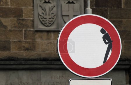Photo for Altered street sign in Florence depicting a man hiding behind the red circle - Royalty Free Image