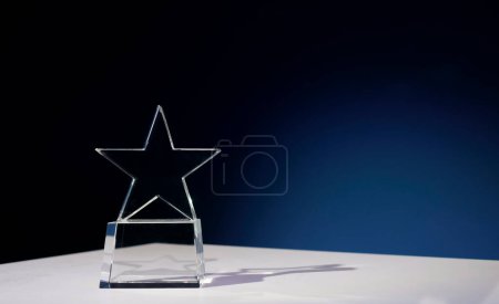Sternförmige Auszeichnung aus Glas auf weißem Tisch mit Scheinwerfer darauf und Kopierraum