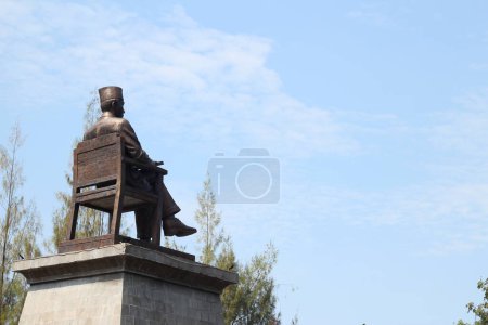 Téléchargez les photos : La statue de Sukarno est vue de derrière, avec une zone vide à droite avec un fond bleu ciel - en image libre de droit