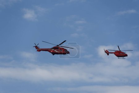 Photo for Thessaloniki, Greece - October 28 2022: Greek firefighting helicopters demonstrating flight air show. An Aerospatiale AS 332L Super Puma and an MBB BK117C-1 during 28 October National Oxi Day parade. - Royalty Free Image