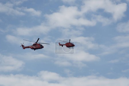 Photo for Thessaloniki, Greece - October 28 2022: Greek firefighting helicopters demonstrating flight air show. An Aerospatiale AS 332L Super Puma and an MBB BK117C-1 during 28 October National Oxi Day parade. - Royalty Free Image