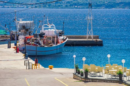 Téléchargez les photos : Un bateau de pêche traditionnel caïque avec des engins amarrés dans un petit port autour d'une mer bleue calme en Grèce. - en image libre de droit