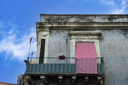 Maison d'architecture traditionnelle de Catane avec un balcon en fer, une tente simple et une façade légèrement délabrée en Sicile, Italie.