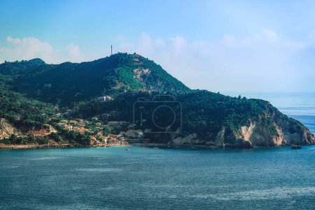 Meerblick auf niedrige Häuser auf dem Hügel oder in Strandnähe, umgeben von einem grünen Wald auf der ionischen Insel Lefkada Griechenland.