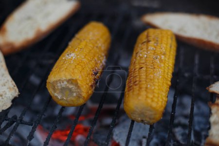 Téléchargez les photos : Cuisson de maïs sur l'épi sur le gril, à l'extérieur de la maison, pendant les vacances - en image libre de droit
