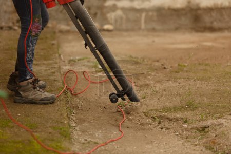 Füße einer Person mit elektrischem Gebläse, die den Garten des Hauses säubert