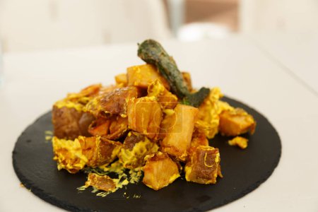 Un plat élégamment présenté avec des légumes rôtis et une sauce jaune luxueuse, mettant en valeur l'art culinaire