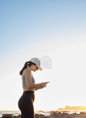 Téléchargez les photos : Profil photo de profil latéral d'une fille avec un capuchon blanc regardant son appareil mobile. - en image libre de droit
