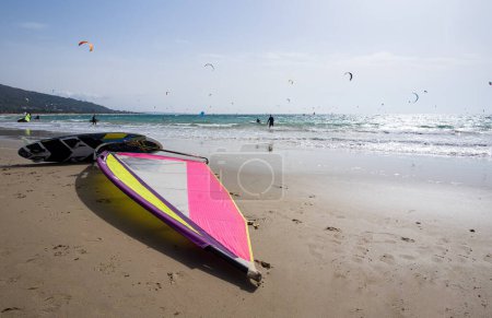 Plage sur la côte de lumière avec mer bleu turquoise. Planche à voile en attente de planche à voile. En arrière-plan cerf-volant méconnaissable surf.