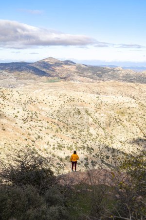 Photo for A girl with her back to nature, admiring the peaceful landscape of the Sierra de las nieves natural park in Andalusia on the horizon. - Royalty Free Image