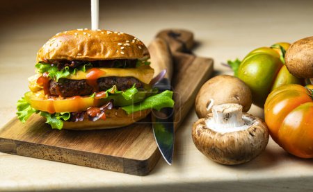 Téléchargez les photos : Burger artisanal, viande juteuse à la tomate fraîche, laitue croustillante et fromage fondu, présenté sur une planche en bois. - en image libre de droit