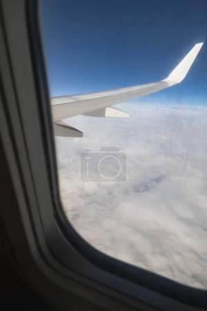 Blick aus dem Flugzeugfenster, Flugzeugflügel und weiße Wolken