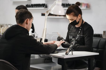 Photo for Male manicure. Female nail service master doing manicure for adult man. Man sitting in beauty salon - Royalty Free Image