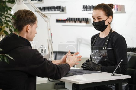 Photo for Male manicure. Close up view of the female nail service master doing manicure for man. Guy tacking care of hands in beauty salon. - Royalty Free Image
