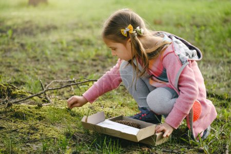 Scavenger hunt for kid in the park. Girl learning about environment. Natural education activity for World Earth day. Exploring in spring.