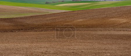 Agricultural farm field of ploughed soil. Landscape with brown ground in early spring. Background copy space