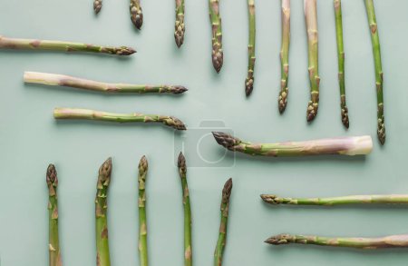 Photo for Brunches of healthy green asparagus on green background, top view, flat lay. Creative composition with sprouts - Royalty Free Image