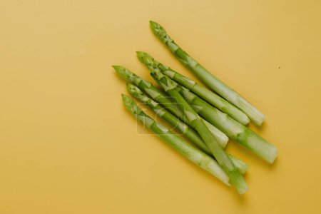 Photo for Fresh green asparagus on yellow background, minimalistic, top view. copy space. Healthy food for balanced diet. - Royalty Free Image