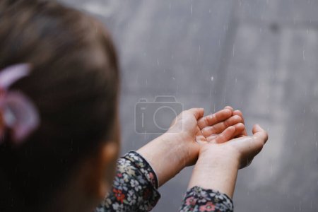 Foto de Niños manos captura de gotas de lluvia, concepto del tiempo. Primer plano de la lluvia cayendo en las manos - Imagen libre de derechos