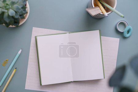 Foto de Cuaderno vacío con material de oficina sobre fondo azul pastel. Oficina piso laico - Imagen libre de derechos
