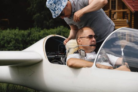 Photo for Soaring club, getting ready for the flight on glider airplane. Small aviation sport. Two man checking cabin instrument panel of vintage airplane - Royalty Free Image