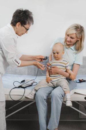 Photo for Child having hearing exam at otolaryngologist. Examining little patient, hearing test of infant kid by audiologist. Mother with baby visiting doctor for checkup - Royalty Free Image