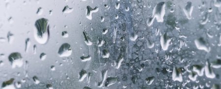 Téléchargez les photos : Bannière gouttes de pluie sur la fenêtre. De l'eau tombe sur le verre. fond naturel, fraîcheur. Temps froid et pluvieux. Gros plan. - en image libre de droit