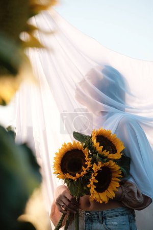 Photo for Unknown woman with sunflower bouquet covered with white fabric outdoors. Natural beauty. Rural summer vacation, Purity and nature concept. Copy space - Royalty Free Image