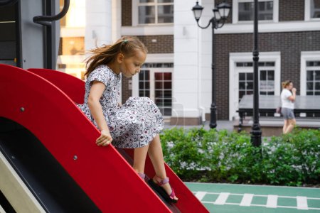 Photo for Girl on the slide. Child playing on playground in the city. Preschooler having fun outdoors in summer - Royalty Free Image