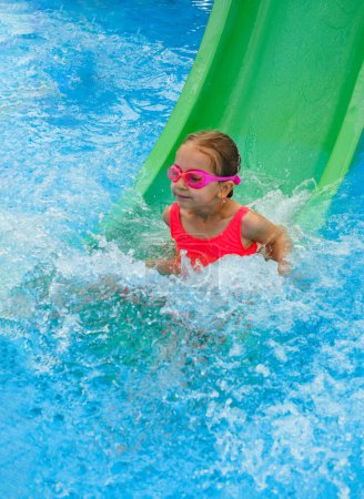 Téléchargez les photos : Enfant heureux dans la piscine extérieure. Fille préscolaire profitant de la baignade d'été. Enfant s'amusant glisser vers le bas, des activités pour le repos et la santé en vacances Sur le bord de la piscine. Se préparer à plonger - en image libre de droit