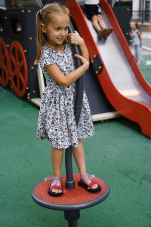 Photo for Child playing on playground in the city. Girl spinning and balancing. Preschooler having fun outdoors in summer. Developing coordination - Royalty Free Image