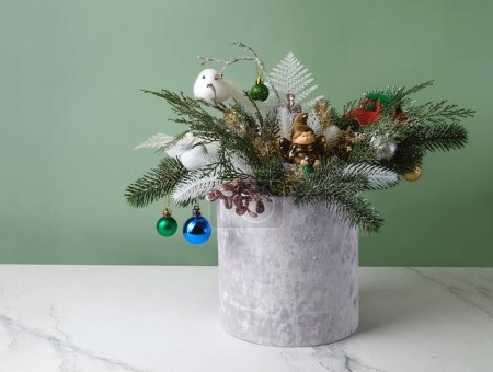 Photo for Christmas composition in velvet grey box with spruce, fern for table decoration. Snowy bunches with bobbles, bird in beautiful packaging, assembled by a florist. Floristic festive decor on the table - Royalty Free Image