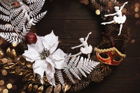 Foto de Corona de Navidad sobre fondo de madera oscura con espacio de copia y bokeh. Decoración festiva rústica vintage. bailarina y máscara de carnaval - Imagen libre de derechos