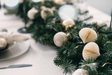 Téléchargez les photos : Décor de Noël en papier artisanal sur la table à manger. Salon intérieur. Table de Noël posée sur des lumières déconcentrées, bokeh. Style écologique, couleur pastel - en image libre de droit