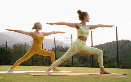 Two woman doing yoga outdoors Mother and adult daughter practicing yoga together. Mature female and young girl having healthy activities. Family Active lifestyle and strength training in mountains