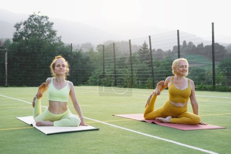 Téléchargez les photos : Deux femmes qui font du yoga en plein air Mère et fille adulte pratiquent ensemble. Femme mûre et jeune fille ayant des activités saines. Famille Style de vie actif et entraînement de force en montagne - en image libre de droit