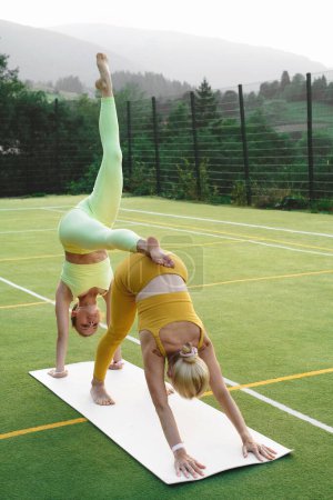 Foto de Dos mujeres haciendo yoga al aire libre Madre e hija adulta practicando juntas. Mujer madura y joven que tiene actividades saludables. Familia Estilo de vida activo y entrenamiento de fuerza en montañas - Imagen libre de derechos