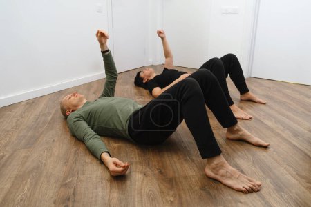 Foto de Ejercicio de rehabilitación. Concepto de fisioterapia. Dos personas tumbadas en el suelo con las manos y las piernas arriba, linfa y mejora del flujo sanguíneo. Método Feldenkrais - Imagen libre de derechos