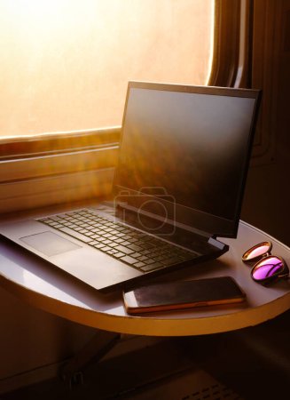 Photo for Working in train on sunset. Laptop standing on the table by the window. Nobody. Laptop computer while traveling with high-speed train. Modern and fast travel concept - Royalty Free Image