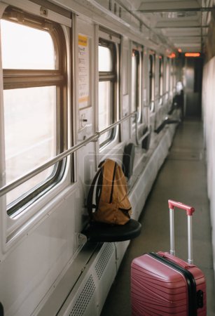 Photo for Red suitcase in the train. Baggage standing in the corridor of night sleeping train, Nobody. Empty wagon, cozy and comfortable travel, sunset light coming from the window. - Royalty Free Image