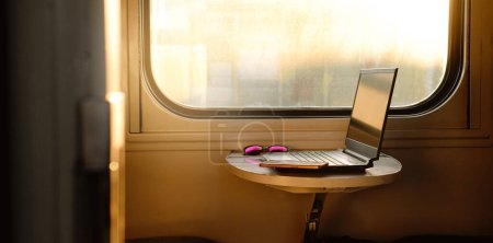 Photo for Working in train on sunset. Laptop standing on the table by the window. Nobody. Laptop computer while traveling with high-speed train. Cozy business travel concept. - Royalty Free Image