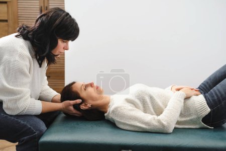 Foto de Mujer Osteópata Terapeuta Examinando la cabeza del paciente para el diagnóstico y tratamiento. Cuidado profesional y alivio del dolor a través de la terapia manual. Copiar espacio - Imagen libre de derechos