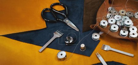 Photo for Tailor workplace accessories. Close up view of the eco leather and tailoring equipment laying on the table. Set of pins, bobbin for a sewing machine, spool of thread, top view - Royalty Free Image