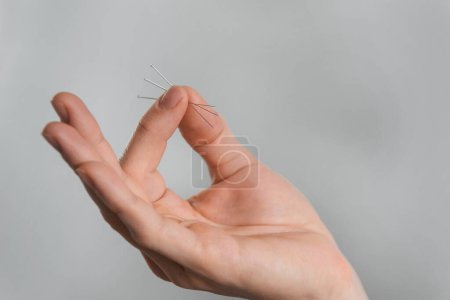 Photo for Acupuncture needles in hands over grey background. Alternative chinese medicine, relieve pain - Royalty Free Image