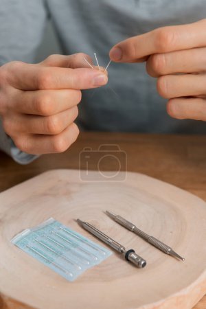 Photo for Acupuncture treatment on mans hands. Rehabilitation using alternative medicine. Acupressure instruments on wooden background. - Royalty Free Image