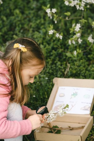 Photo for Scavenger hunt for kid in the park. Girl learning about environment. Natural education activity for World Earth day. Exploring in spring. - Royalty Free Image